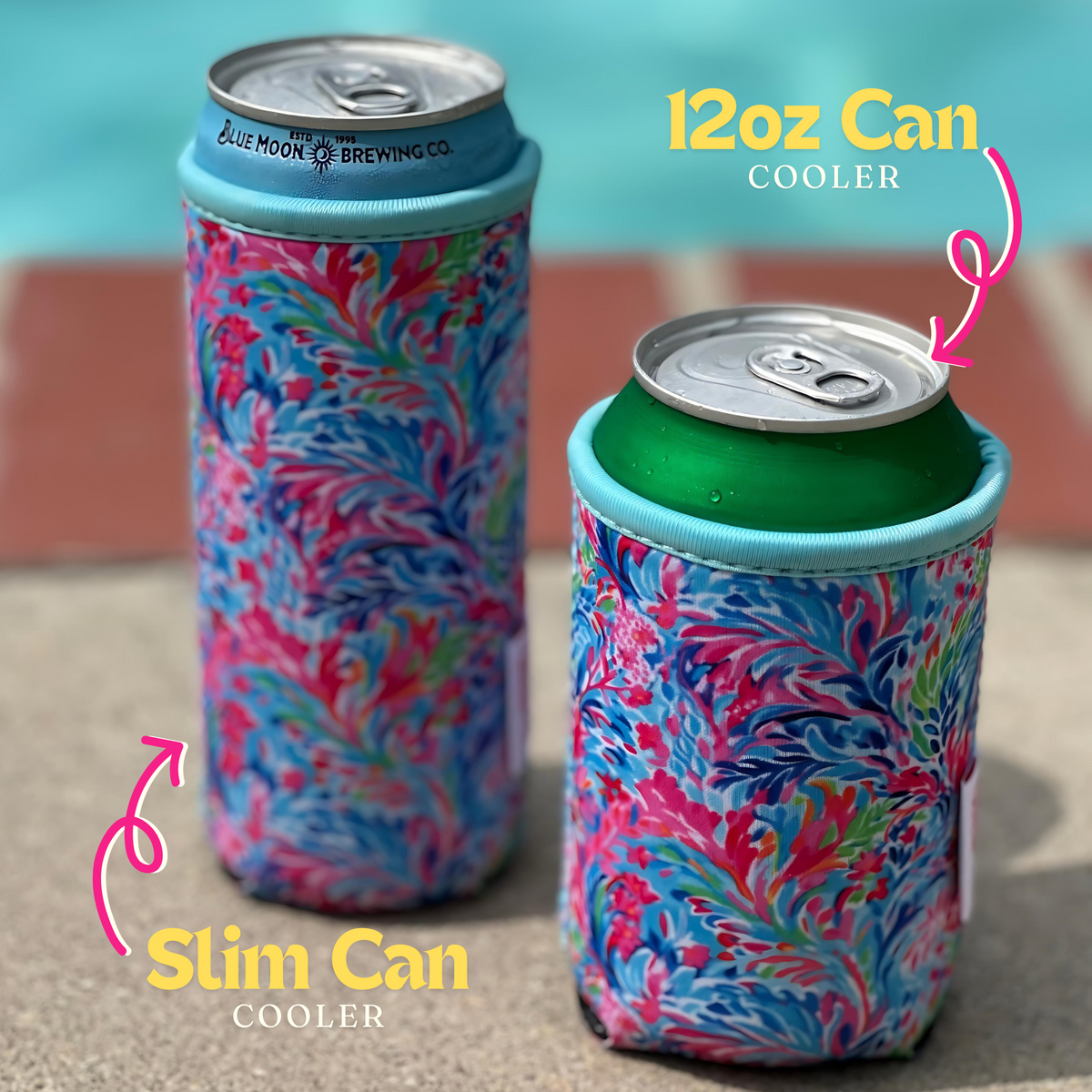 Two vibrant, floral-patterned Emerson West Resort Blooms Neoprene Can Coolers are shown by a poolside, perfect for poolside relaxation. The left cooler fits a 12 oz slim can while the right cooler holds a standard 12 oz can. Both coolers boast colorful, intricate designs with visible text indicating their respective can sizes.