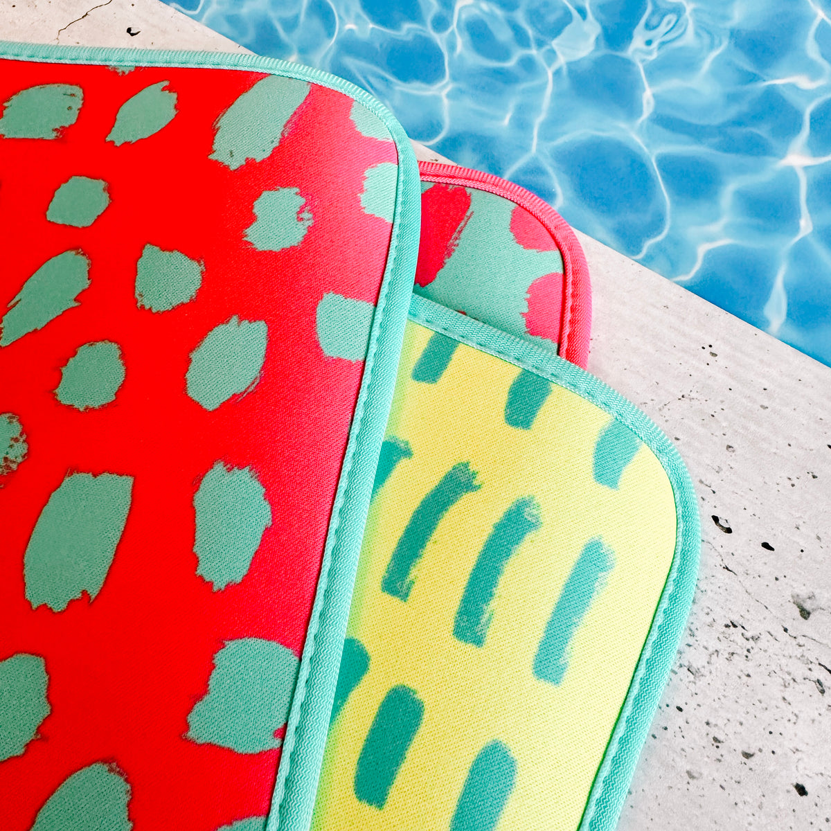 Oh So Bright Collection poolside seating mats stacked by a swimming pool, ready for a fun day with Emerson West. Poolside mat and pool accessory.