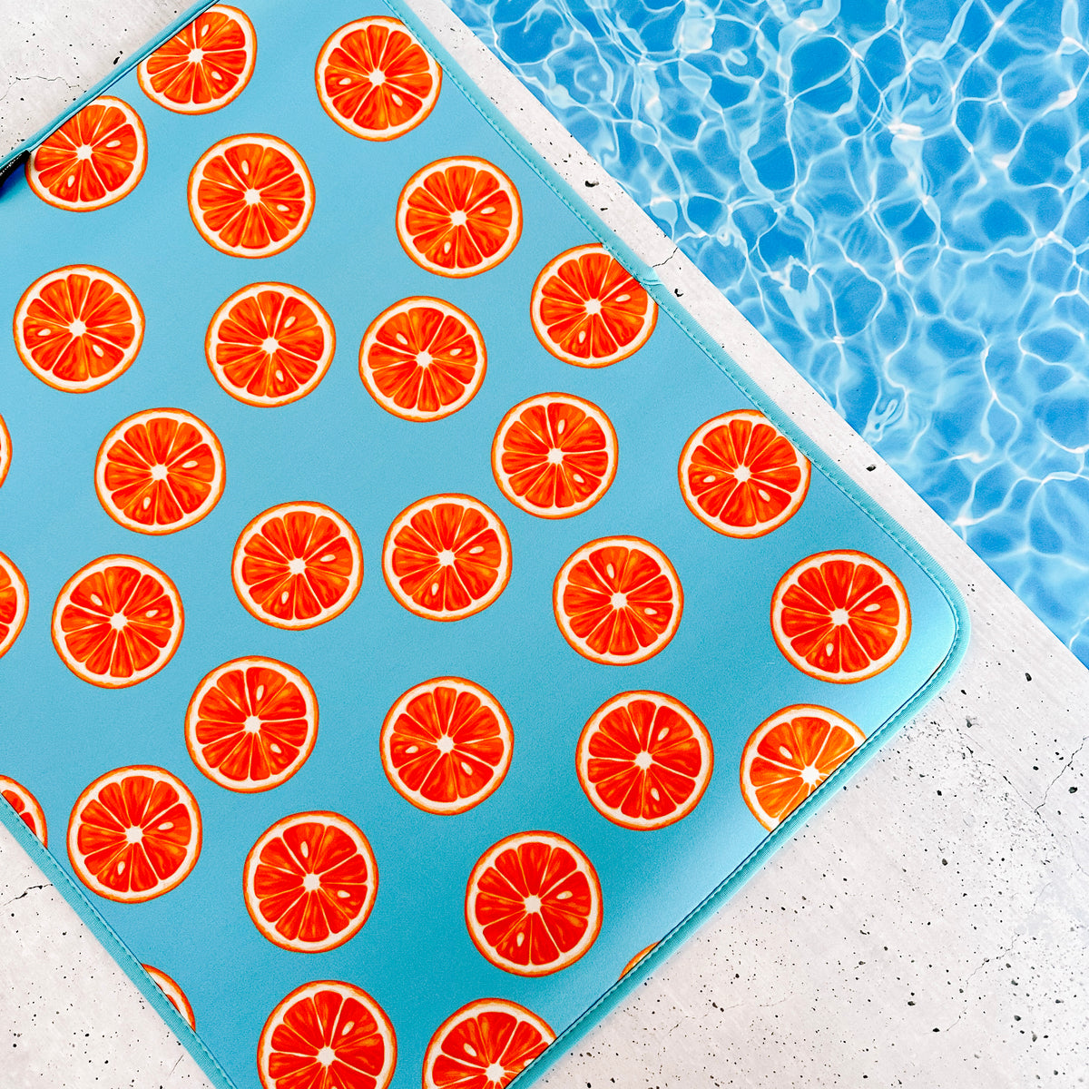 A vibrant poolside scene with an Emerson West Oranges Poolside Seating Mat resting next to a shimmering blue swimming pool, signaling fun and relaxation under the sun.