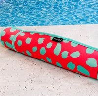 A vibrant, pink neoprene poolside seating mat  with a teal cheetah print design resting on the poolside, ready for a refreshing aquatic adventure on the quick-dry Emerson West Poolside Seating Mat.