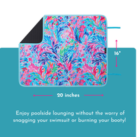 A vibrant Emerson West Resort Blooms Poolside Seating Mat with a colorful, intricate floral design in shades of pink, blue, and green. The quick-dry mat measures 20 inches by 16 inches. The text underneath reads: "Enjoy poolside lounging without the worry of snagging your swimsuit or burning your booty!